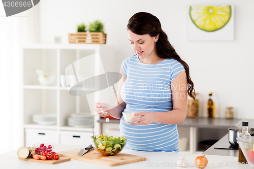 Image of pregnant woman cooking vegetable salad at home