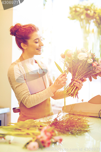 Image of smiling florist woman making bunch at flower shop