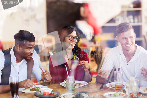 Image of happy friends eating at restaurant