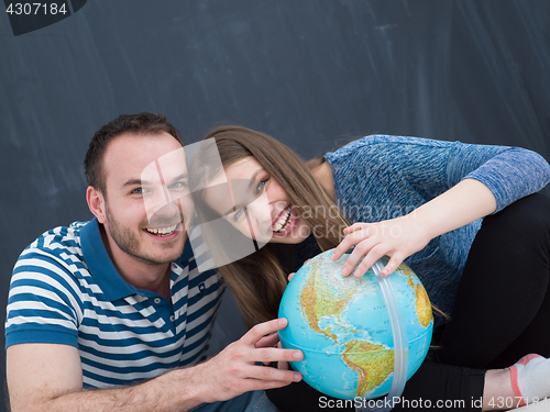 Image of couple in casual clothing investigating globe