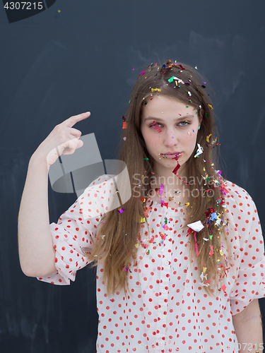 Image of woman blowing confetti in the air isolated over gray