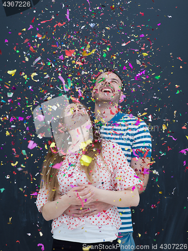 Image of couple blowing confetti in the air isolated over gray