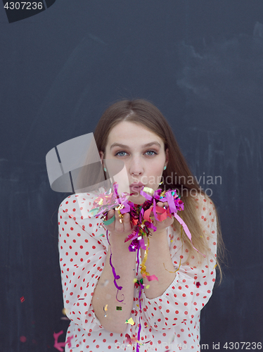 Image of woman blowing confetti in the air isolated over gray