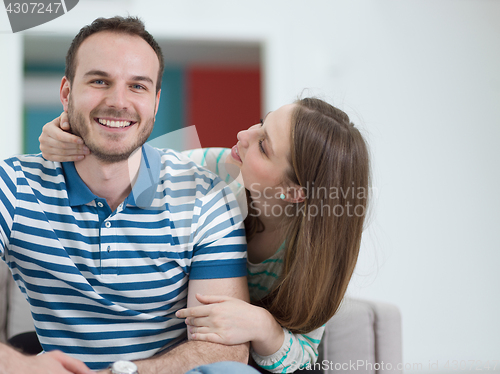 Image of young handsome couple hugging on the sofa