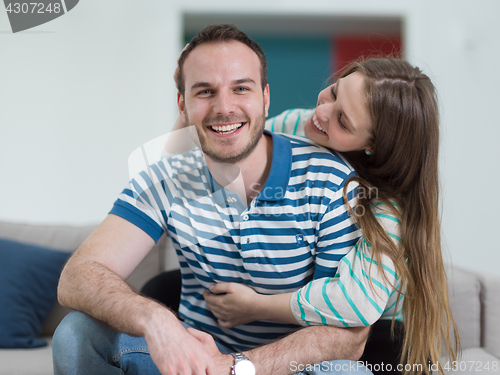 Image of young handsome couple hugging on the sofa