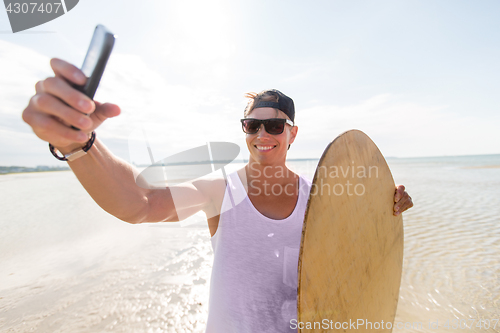 Image of happy young man with skimboard on summer beach