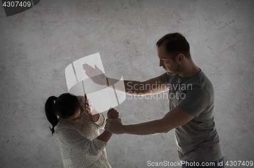 Image of couple having fight and man beating woman