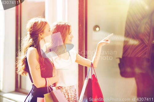 Image of happy women with shopping bags at shop window