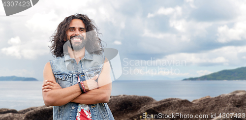 Image of smiling hippie man in denim vest on island