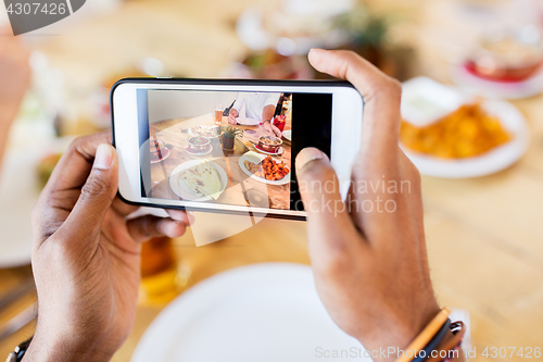 Image of hands with smartphone picturing food at restaurant