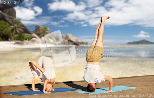 Image of couple making yoga over tropical beach background