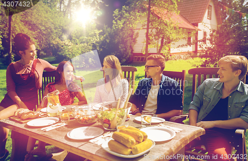 Image of happy friends having dinner at summer garden party