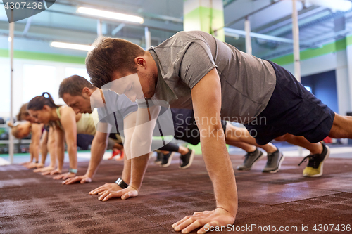 Image of group of people doing straight arm plank in gym