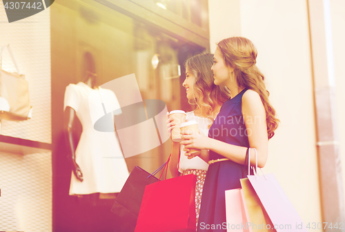 Image of young women with shopping bags and coffee at shop