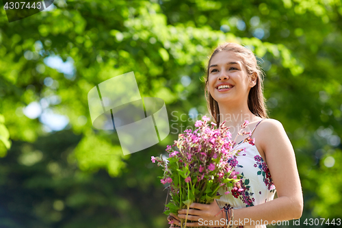 Image of happy young woman with flowers in summer park