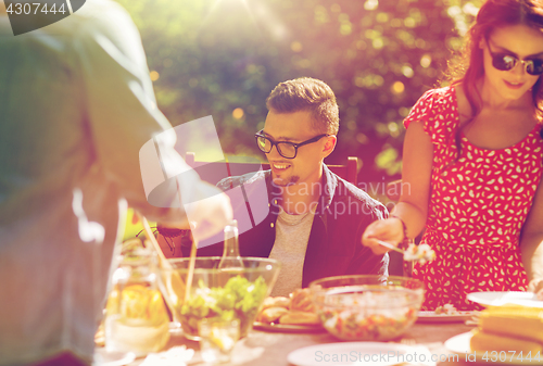 Image of happy friends having dinner at summer garden party