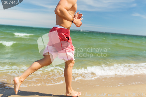 Image of happy man running along summer beach