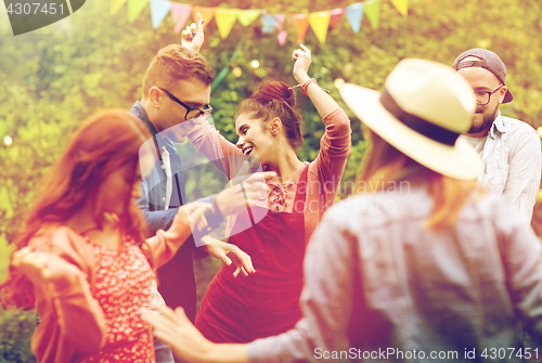 Image of happy friends dancing at summer party in garden