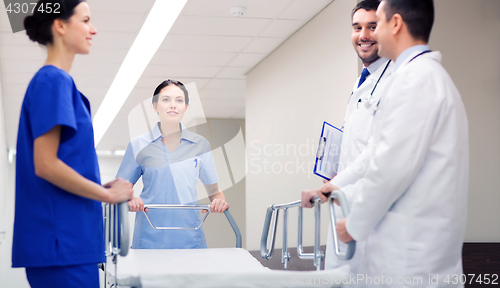 Image of group of happy doctors with gurney at hospital