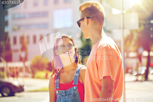 Image of happy teenage couple looking at each other in city