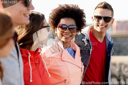 Image of happy teenage friends in shades talking on street