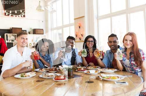 Image of happy friends eating and drinking at restaurant