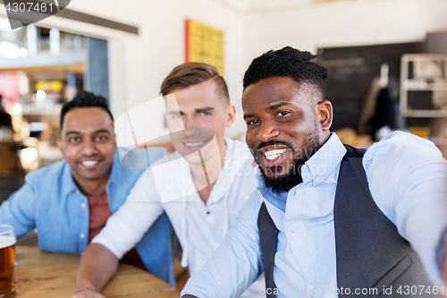 Image of friends taking selfie and drinking beer at bar