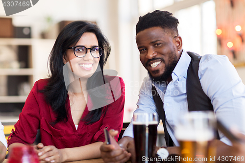 Image of happy man and woman with smartphone at bar