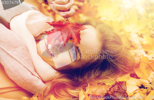 Image of beautiful happy woman lying on autumn leaves