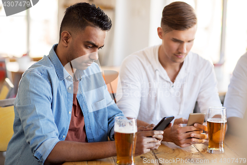 Image of male friends with smartphone drinking beer at bar