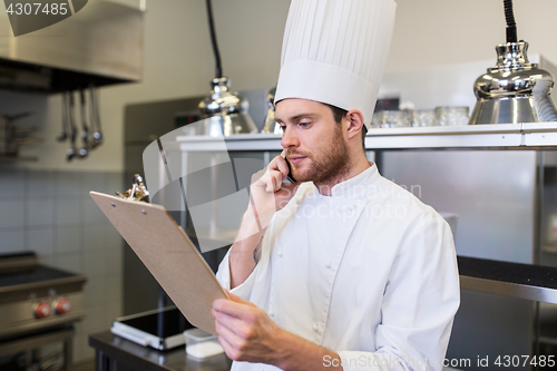 Image of chef cook calling on smartphone at restaurant kitchen