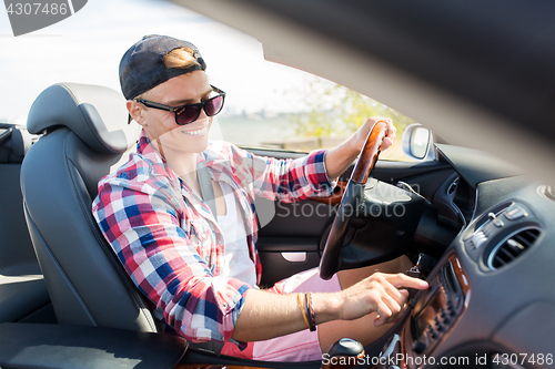 Image of happy young man driving convertible car