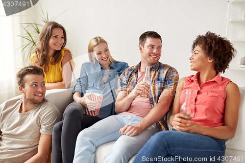 Image of happy friends with popcorn and beer at home