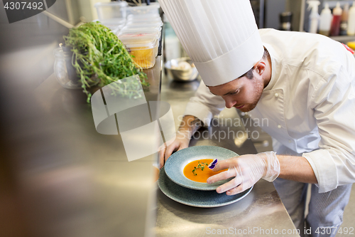 Image of male chef decorating dish with pansy flower