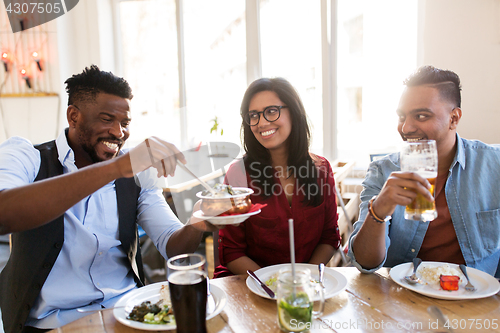 Image of happy friends eating at restaurant
