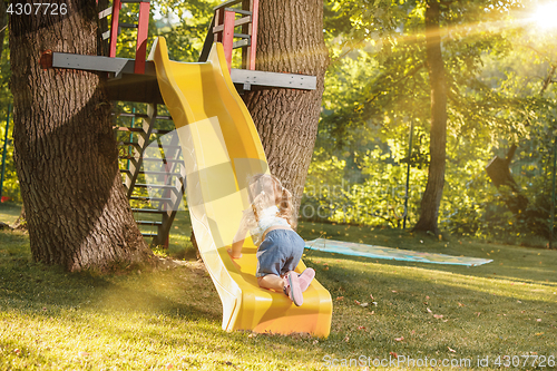 Image of Happy little girl rolling down the hill on the playground