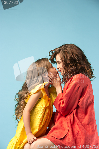 Image of Pregnant mother with teen daughter. Family studio portrait over blue background