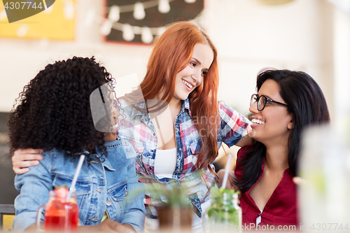 Image of happy female friends with drinks at bar