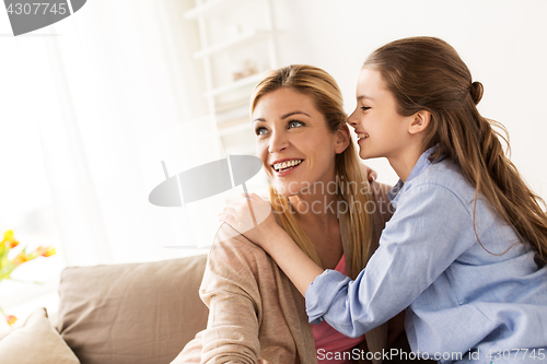 Image of happy girl whispering secret to her mother at home