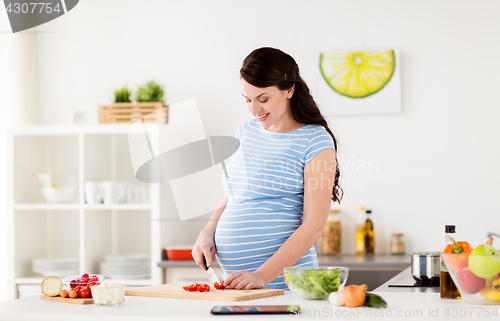 Image of pregnant woman cooking vegetables at home