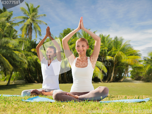 Image of couple doing yoga in lotus pose outdoors