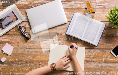 Image of hands with book writing to notebook at table