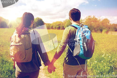 Image of happy couple with backpacks hiking outdoors