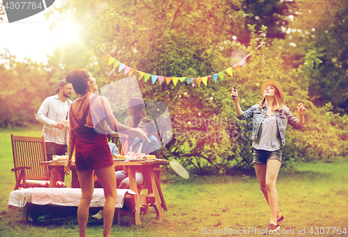 Image of happy friends playing badminton at summer garden