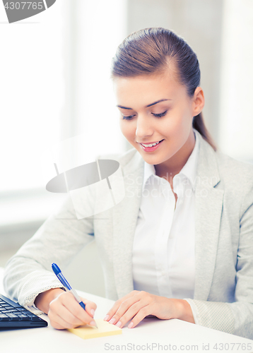 Image of businesswoman writing on sticky note