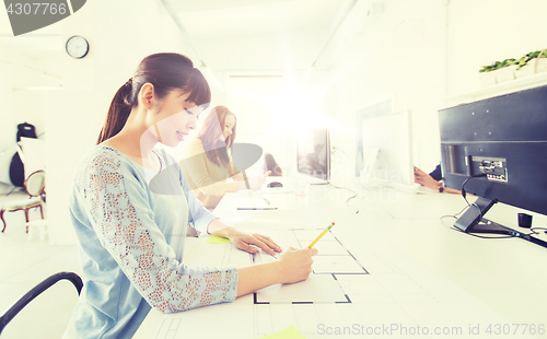 Image of architect woman drawing on blueprint at office