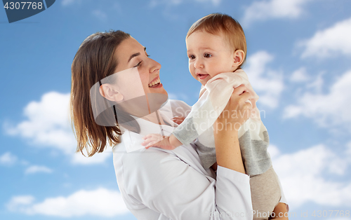 Image of happy doctor or pediatrician with baby over sky