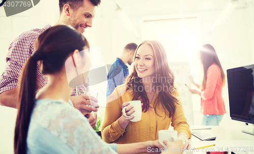 Image of happy creative team drinking coffee at office