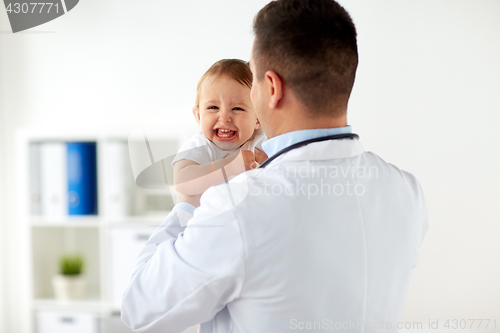 Image of happy doctor or pediatrician with baby at clinic