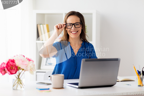 Image of happy woman with laptop working at home or office